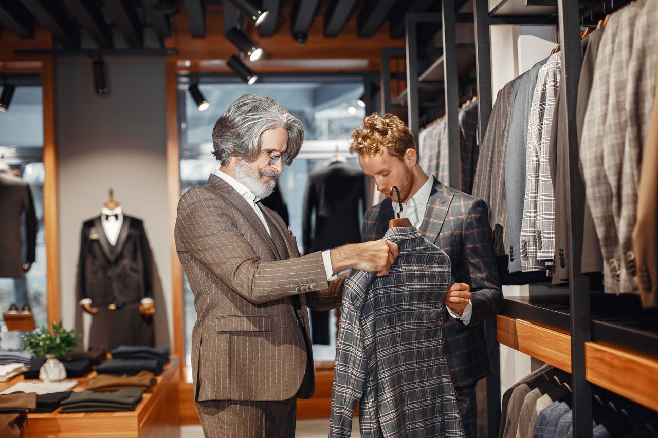 Two men choosing a suit in a stylish clothing boutique. Indoor shopping scene.